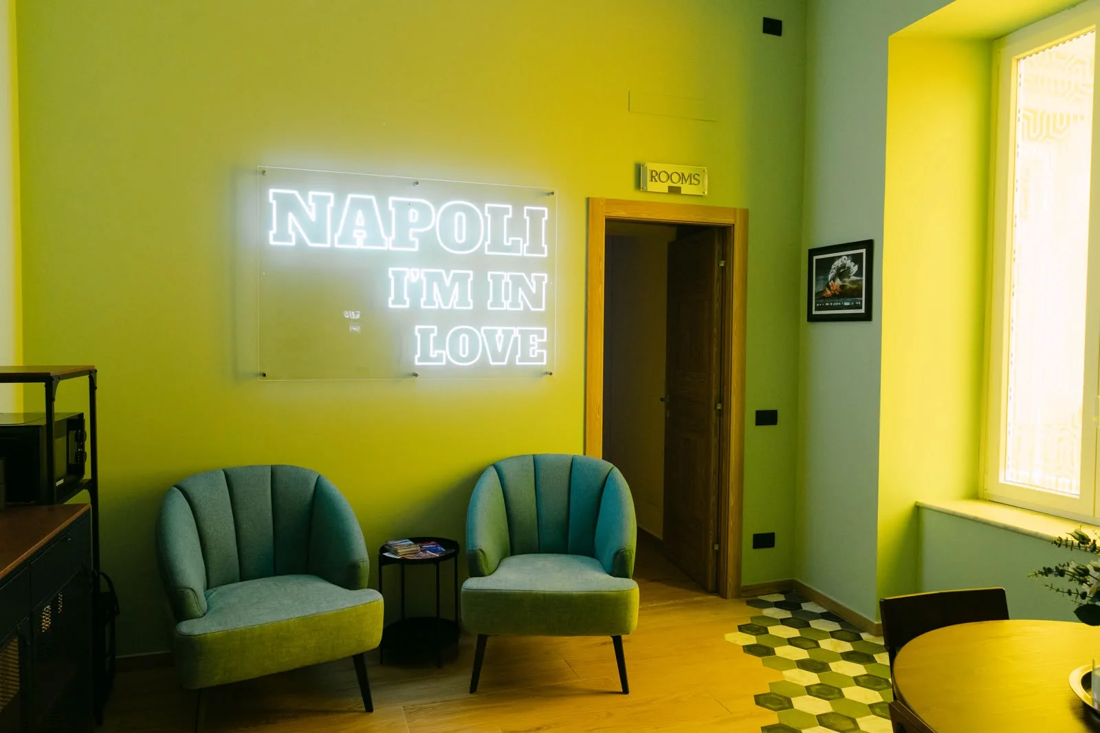 La sala comune di Domus San Gregorii, con poltrone verdi e l'insegna Napoli I'm in love