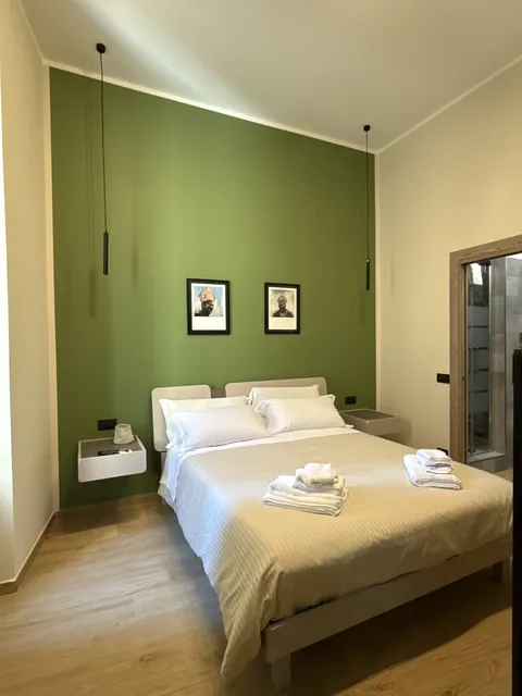 Camera Via Duomo: parete verde, letto matrimoniale e dettagli in legno