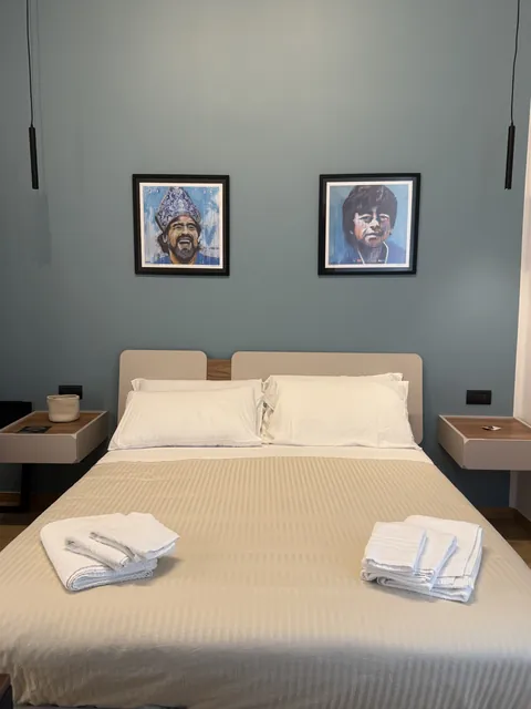 Camera Largo Maradona: letto matrimoniale davanti a una parete grigio azzurra
