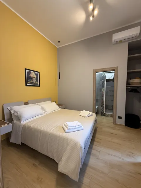 Camera Via Parthenope: letto matrimoniale, luce naturale e parete giallo sole